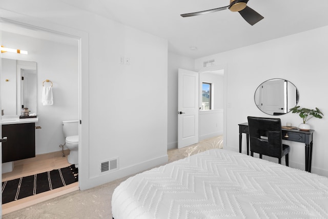 bedroom featuring light colored carpet, ceiling fan, and ensuite bathroom