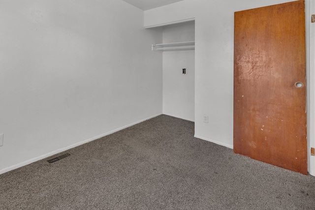 unfurnished bedroom featuring dark colored carpet and a closet