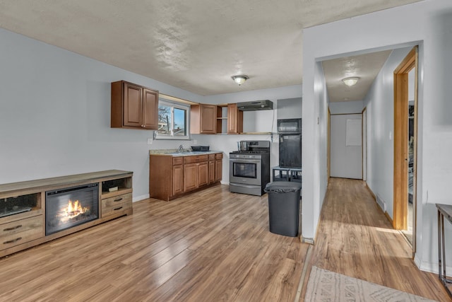 kitchen featuring gas range, sink, light hardwood / wood-style floors, and a textured ceiling