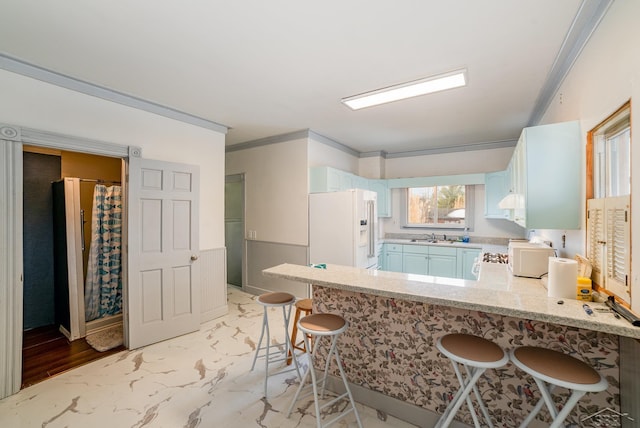 kitchen with sink, crown molding, a breakfast bar area, white fridge with ice dispenser, and kitchen peninsula