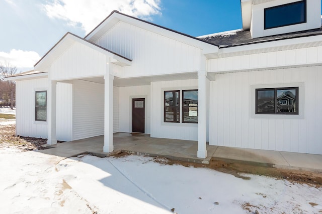 snow covered property entrance with covered porch