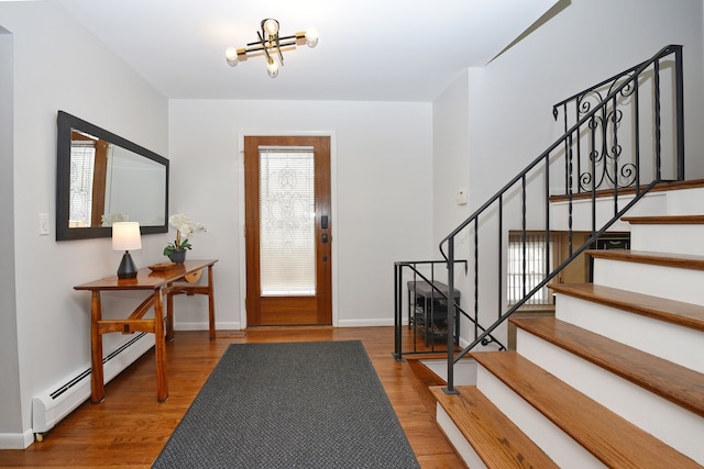 entrance foyer with a baseboard radiator, a chandelier, and hardwood / wood-style floors