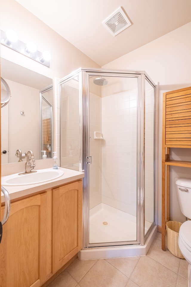 bathroom featuring tile patterned flooring, walk in shower, vanity, and toilet