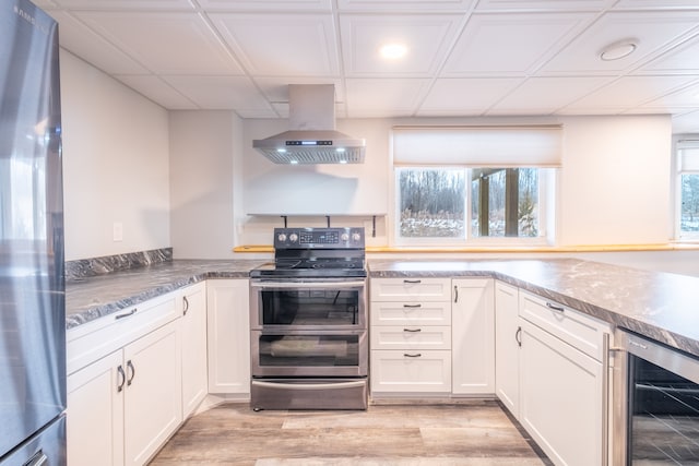 kitchen featuring appliances with stainless steel finishes, white cabinetry, beverage cooler, island exhaust hood, and light hardwood / wood-style floors