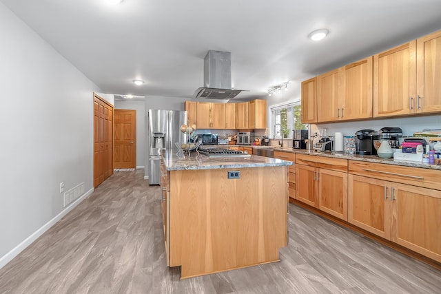 kitchen with island range hood, a center island, stainless steel appliances, light stone countertops, and light brown cabinets