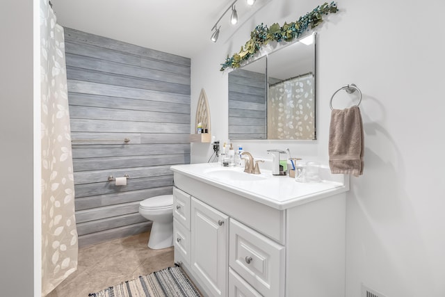 bathroom featuring vanity, wood walls, and toilet