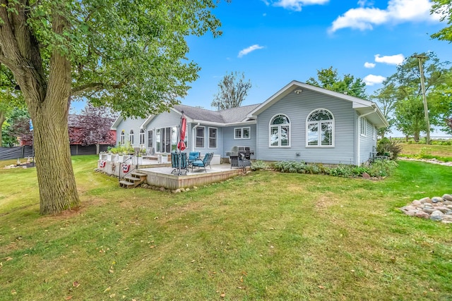 back of property with a deck and a lawn