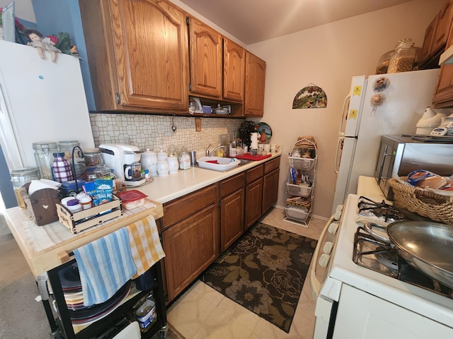 kitchen featuring sink, white appliances, decorative backsplash, and light tile patterned floors