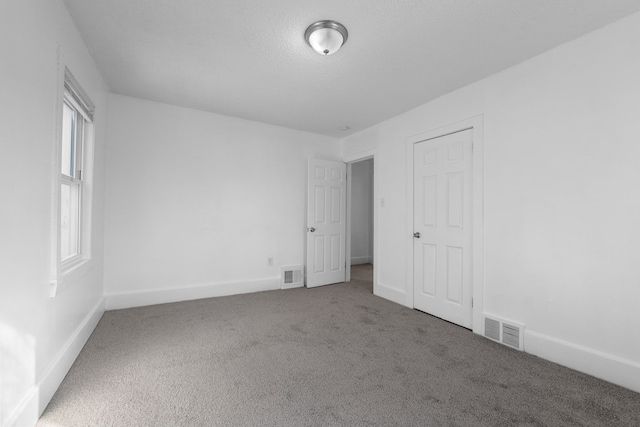 spare room featuring carpet and a textured ceiling