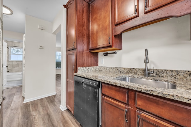 kitchen with light stone counters, black dishwasher, sink, and light hardwood / wood-style flooring