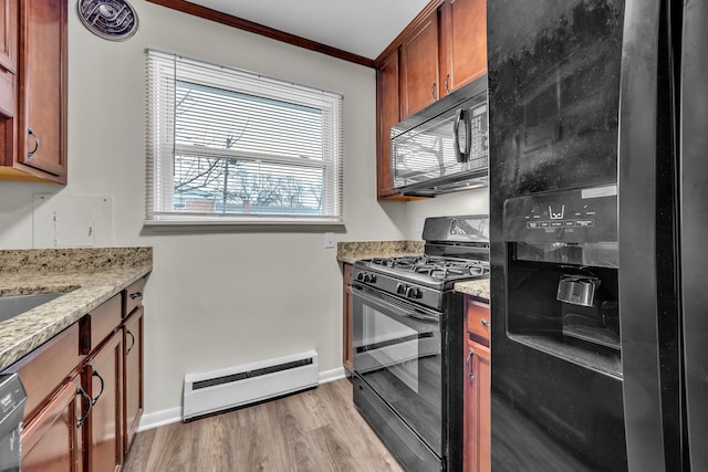 kitchen featuring light hardwood / wood-style flooring, a baseboard heating unit, light stone counters, black appliances, and ornamental molding