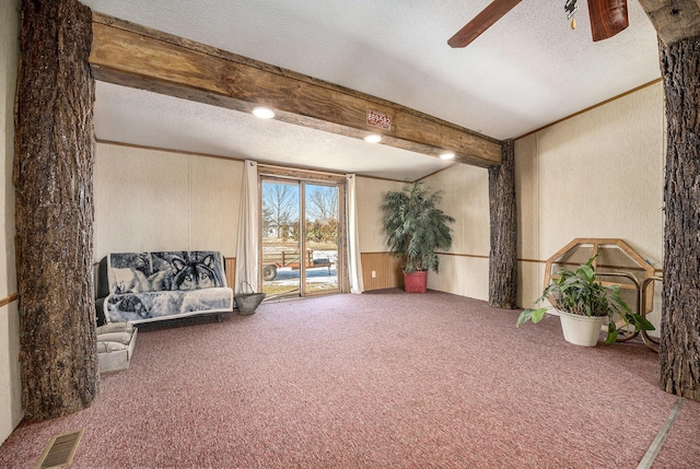 living area with ceiling fan, carpet, a textured ceiling, and beam ceiling