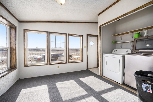 clothes washing area with light carpet, washer and dryer, and a textured ceiling