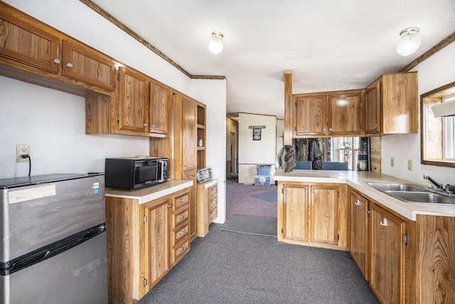 kitchen featuring sink, a textured ceiling, stainless steel refrigerator, kitchen peninsula, and dark carpet