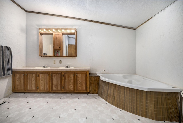 bathroom featuring vanity, ornamental molding, tiled bath, and a textured ceiling