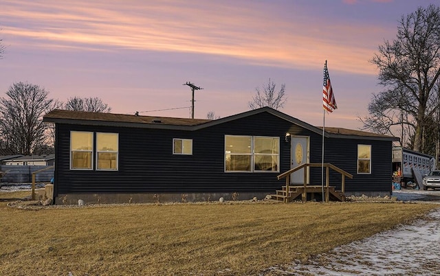 back house at dusk featuring a lawn