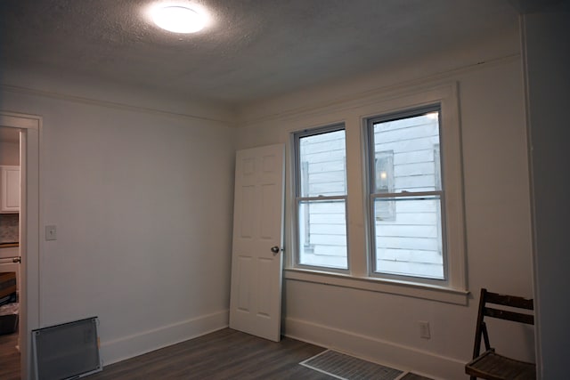 unfurnished room with a wealth of natural light, dark hardwood / wood-style floors, and a textured ceiling