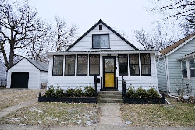 bungalow-style house featuring an outbuilding, a garage, and a sunroom