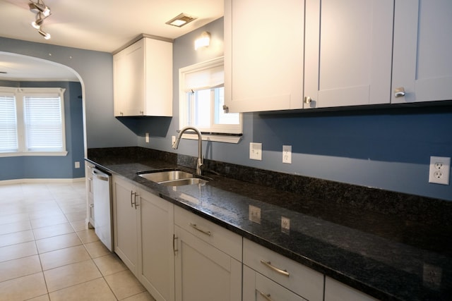 kitchen featuring dishwasher, white cabinetry, sink, dark stone countertops, and light tile patterned floors