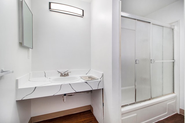 bathroom with sink, hardwood / wood-style flooring, and bath / shower combo with glass door