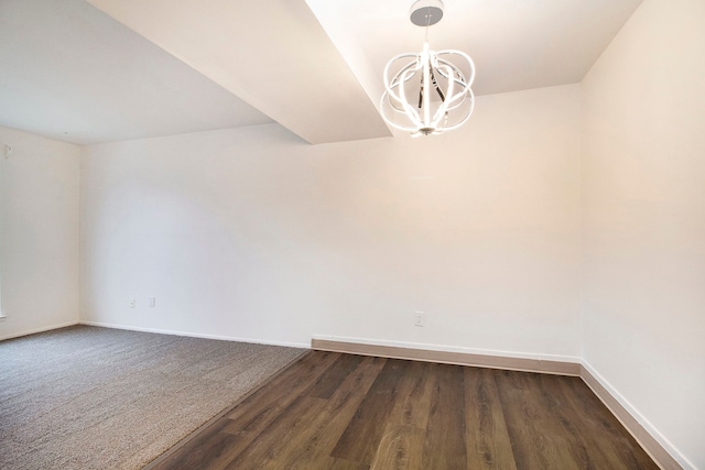 spare room with an inviting chandelier and dark wood-type flooring