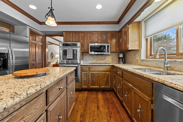 kitchen featuring pendant lighting, sink, crown molding, stainless steel appliances, and light stone countertops