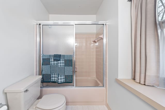 bathroom featuring shower / bath combination with glass door and toilet