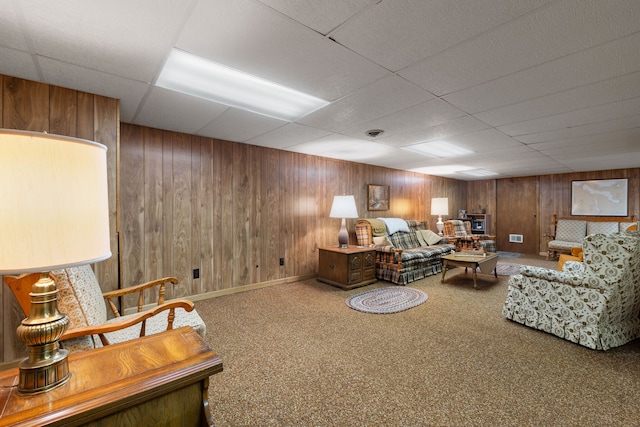 living room with carpet flooring, a paneled ceiling, and wood walls