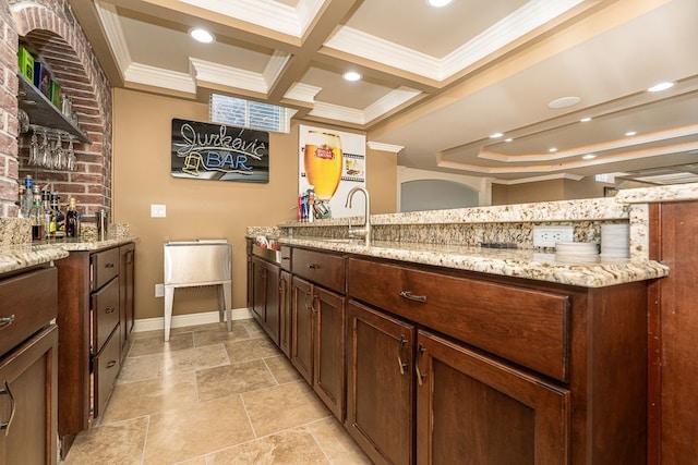 interior space with ornamental molding, coffered ceiling, light stone countertops, and sink