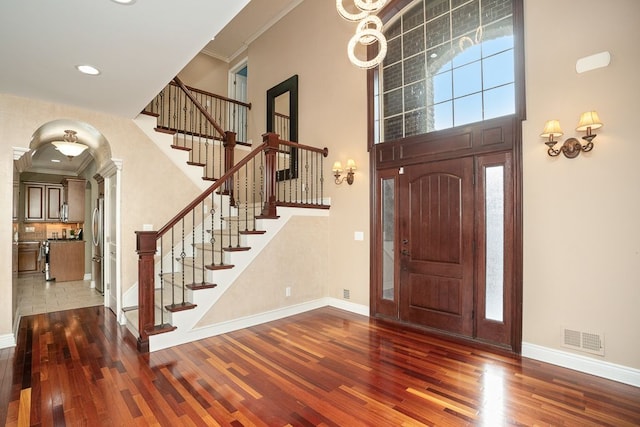 foyer with a high ceiling, ornamental molding, and wood-type flooring