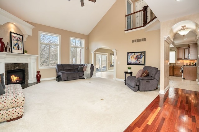 living room featuring a premium fireplace, high vaulted ceiling, and carpet