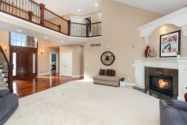 living room with ornamental molding, a fireplace, hardwood / wood-style floors, and a high ceiling