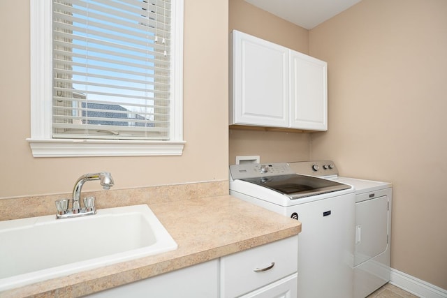 clothes washing area featuring cabinets, sink, and independent washer and dryer