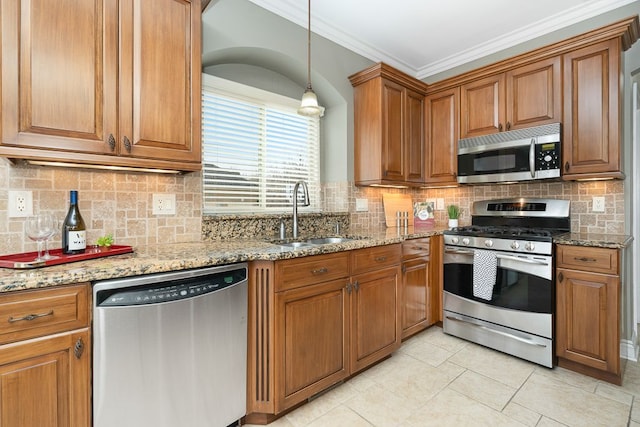 kitchen featuring sink, crown molding, stainless steel appliances, light stone counters, and decorative light fixtures