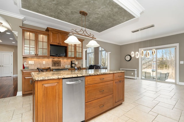 kitchen featuring a raised ceiling, light stone countertops, hanging light fixtures, and a center island with sink