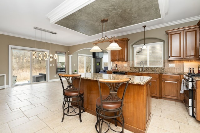 kitchen featuring light stone counters, hanging light fixtures, appliances with stainless steel finishes, a kitchen island, and decorative backsplash