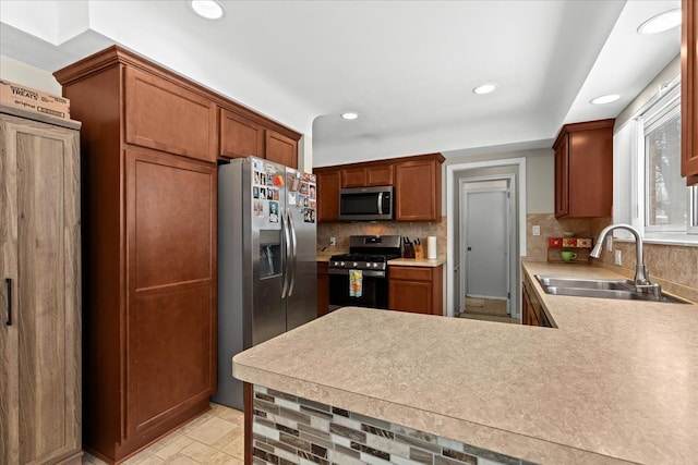 kitchen with appliances with stainless steel finishes, sink, kitchen peninsula, and decorative backsplash