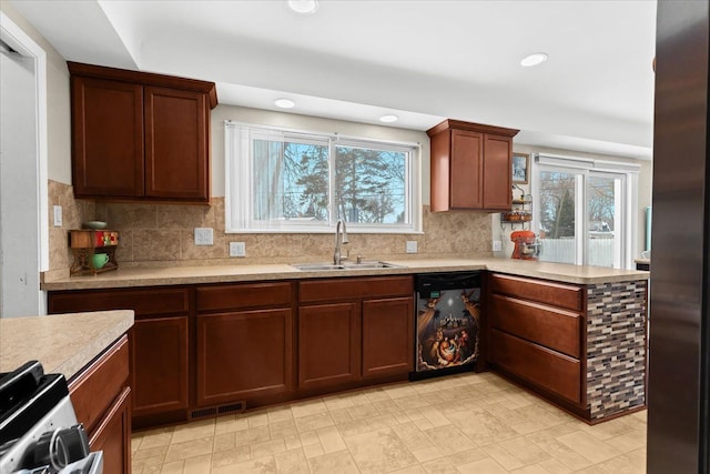 kitchen featuring sink, range, stainless steel refrigerator, dishwashing machine, and decorative backsplash