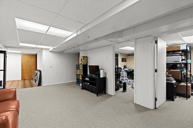 basement with a paneled ceiling and light carpet