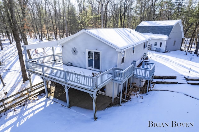 snow covered back of property featuring a wooden deck