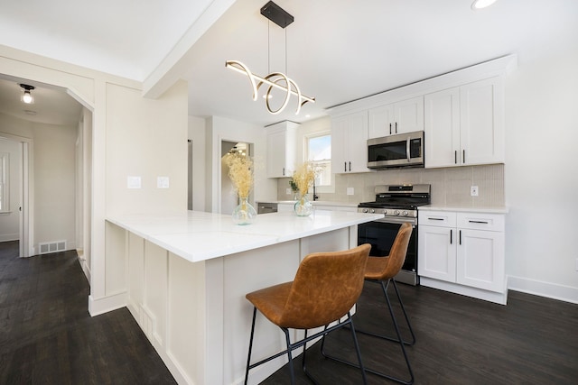 kitchen with white cabinetry, stainless steel appliances, a kitchen bar, decorative backsplash, and kitchen peninsula