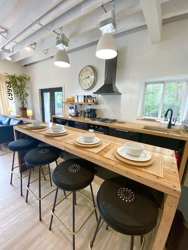 kitchen featuring island range hood, wood counters, beamed ceiling, sink, and light hardwood / wood-style flooring