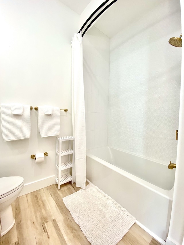 bathroom featuring hardwood / wood-style floors, shower / bath combination with curtain, and toilet