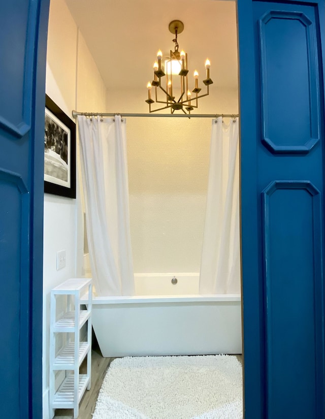 bathroom featuring shower / tub combo with curtain and a chandelier