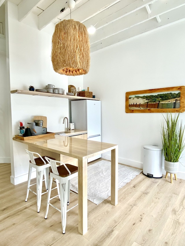 interior space featuring beamed ceiling, sink, wooden counters, white refrigerator, and light wood-type flooring