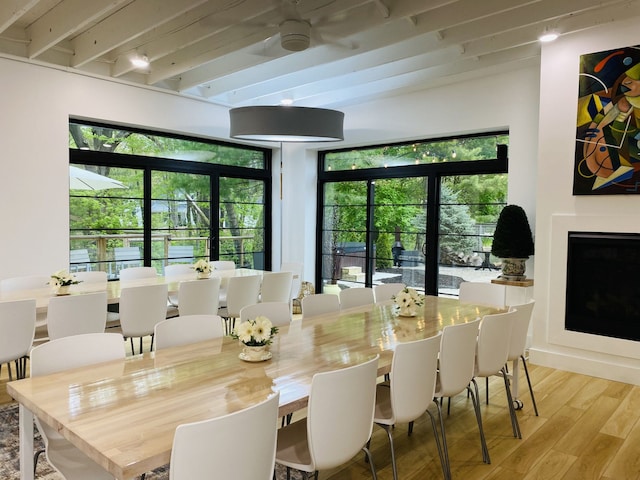 dining space featuring beamed ceiling and light wood-type flooring