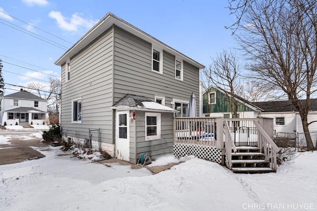 snow covered rear of property with a wooden deck