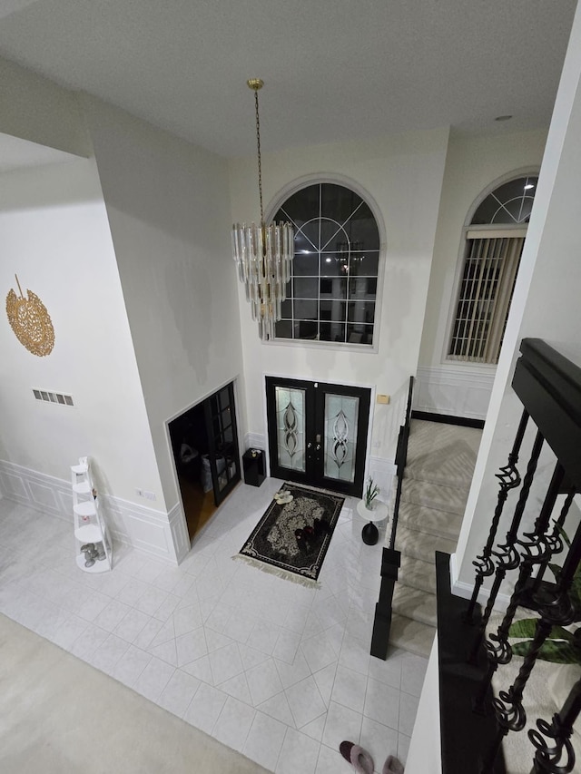 tiled entryway with an inviting chandelier and french doors