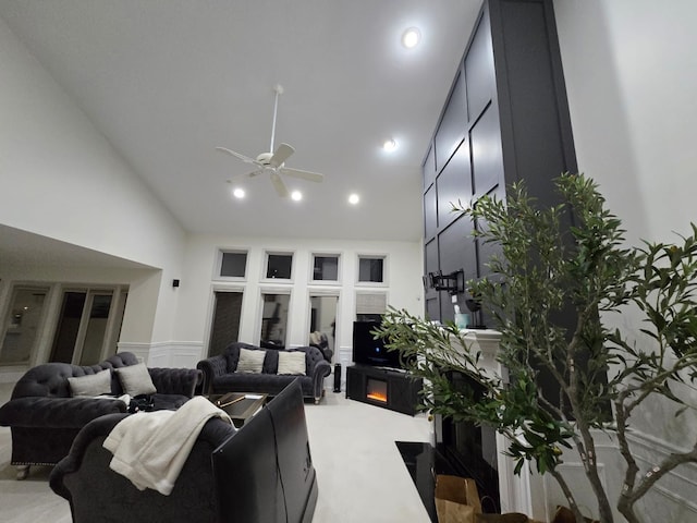 living room featuring light colored carpet, ceiling fan, and high vaulted ceiling