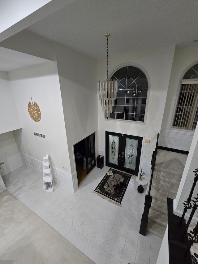 foyer with light tile patterned floors, a notable chandelier, and french doors